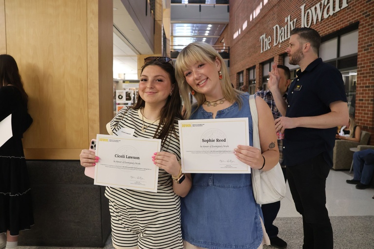 This is a photo of two students holding their scholarships.