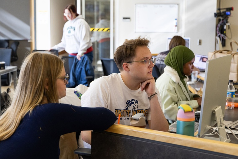 This is a photo of Greta Shaub, Mitchell Brinkmeyer and Kabedi Mutamba looking at photos.
