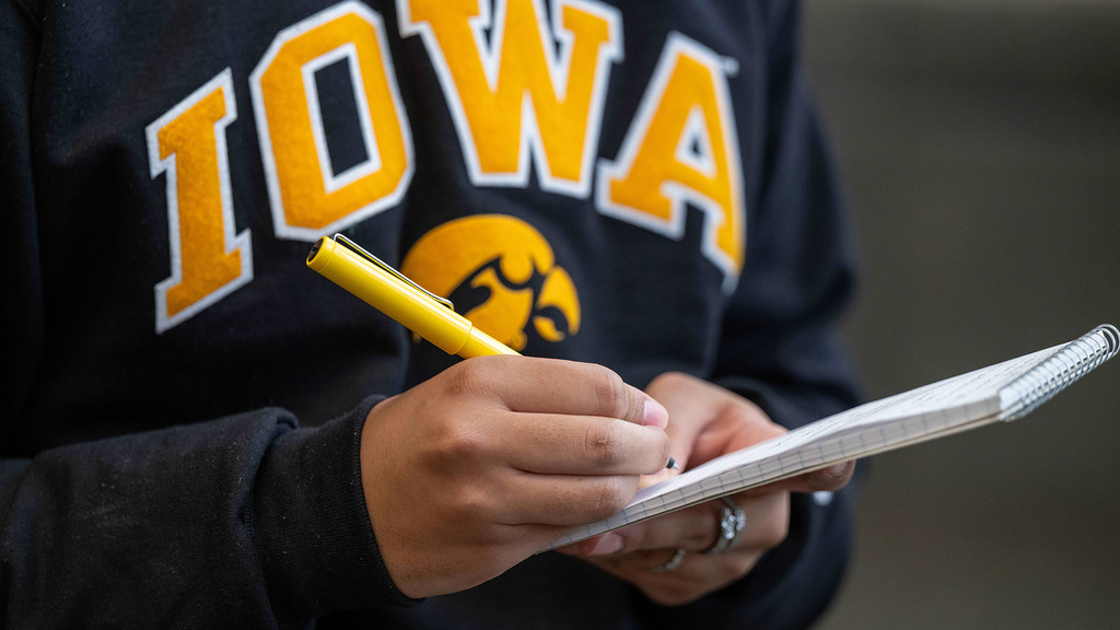 a journalist uses a pen to write notes in a small notebook